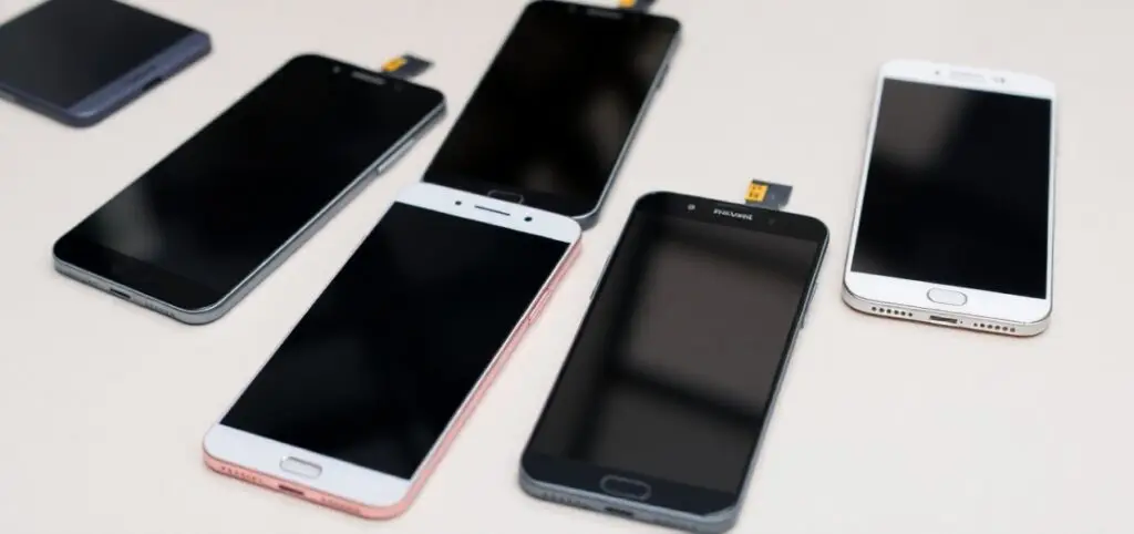 A group of six smartphones with black screens are laid out on a light surface. Mobile Phone Screen